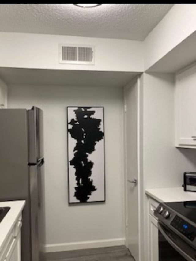 2800 Jeanetta St Unit 2104, Houston, TX 77063 - kitchen featuring light countertops, visible vents, a textured ceiling, appliances with stainless steel finishes, and white cabinetry