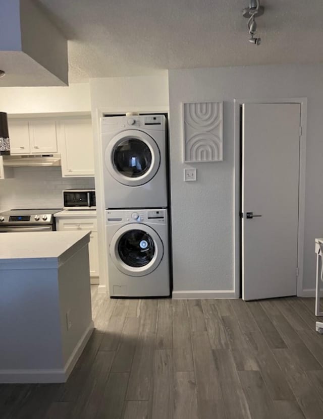 2800 Jeanetta St Unit 2104, Houston, TX 77063 - clothes washing area featuring stacked washer / drying machine, laundry area, wood finished floors, rail lighting, and baseboards