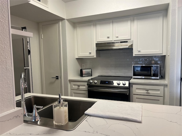 2800 Jeanetta St Unit 2104, Houston, TX 77063 - kitchen with white cabinets, under cabinet range hood, stainless steel appliances, backsplash, and visible vents