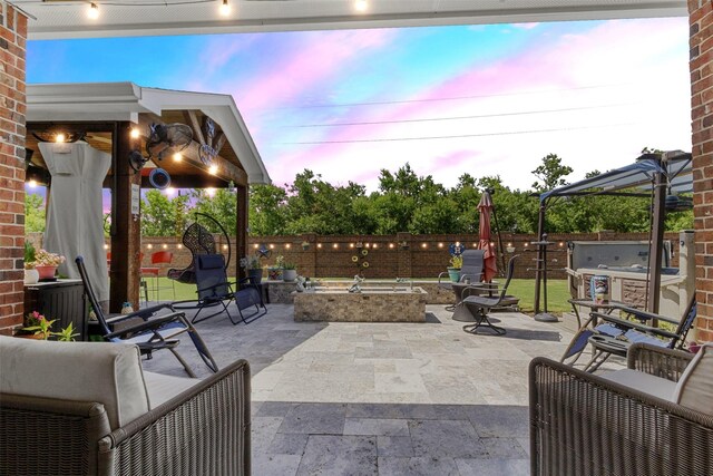 7407 Tudor Heights Ln, Spring, TX 77379 - patio terrace at dusk with a patio area, an outdoor fire pit, exterior kitchen, and a fenced backyard