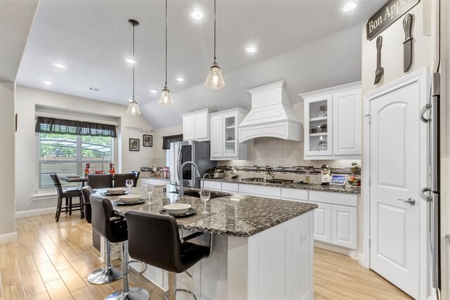 7407 Tudor Heights Ln, Spring, TX 77379 - kitchen with a sink, custom exhaust hood, tasteful backsplash, light wood-style floors, and white cabinets
