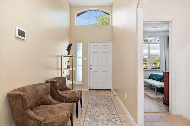 entrance foyer featuring a wealth of natural light, light tile patterned flooring, a high ceiling, and baseboards