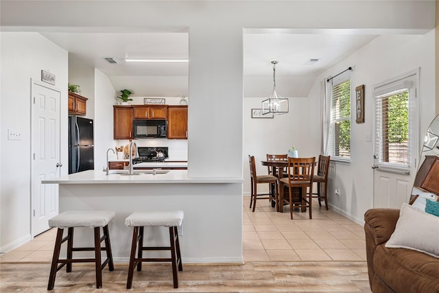 kitchen with brown cabinets, lofted ceiling, a sink, and black appliances