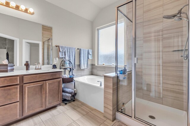 full bathroom featuring a shower stall, vanity, a bath, vaulted ceiling, and tile patterned flooring
