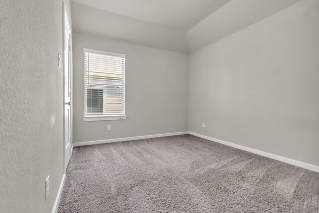 unfurnished room featuring lofted ceiling, carpet flooring, and baseboards