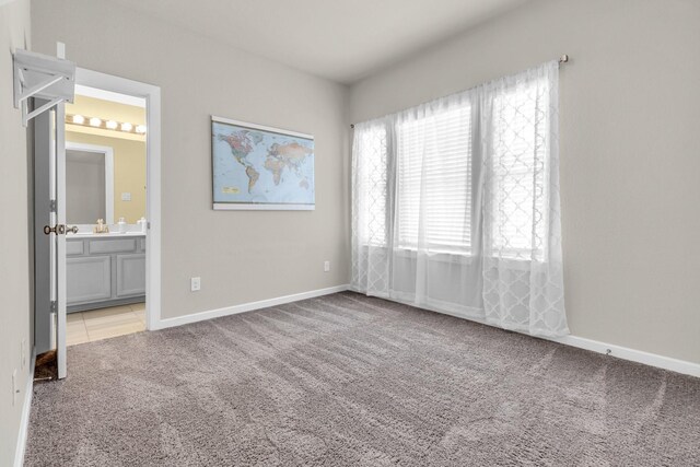 unfurnished bedroom featuring connected bathroom, carpet floors, and baseboards