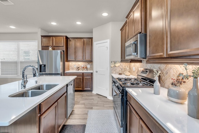 kitchen featuring appliances with stainless steel finishes, light countertops, recessed lighting, and a sink