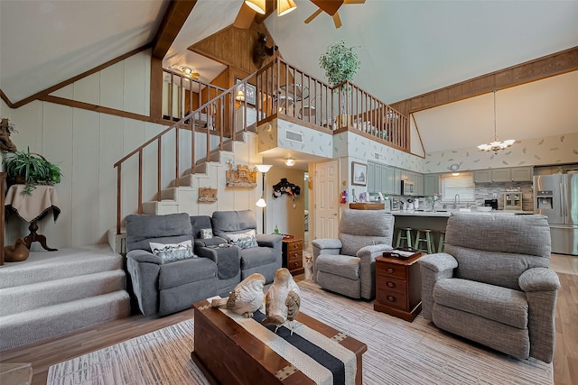 living area with light wood finished floors, high vaulted ceiling, and stairway