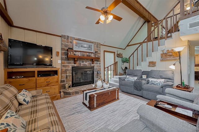 living room featuring ceiling fan, a stone fireplace, high vaulted ceiling, and stairway