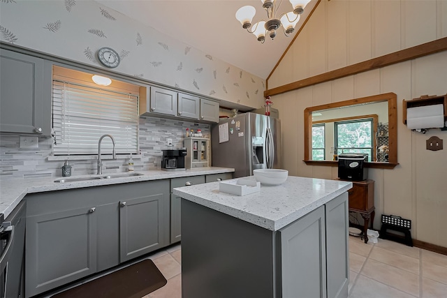 kitchen featuring a sink, decorative backsplash, light tile patterned floors, gray cabinets, and appliances with stainless steel finishes