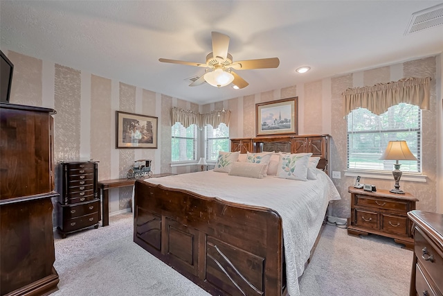 bedroom with wallpapered walls, visible vents, light colored carpet, and ceiling fan