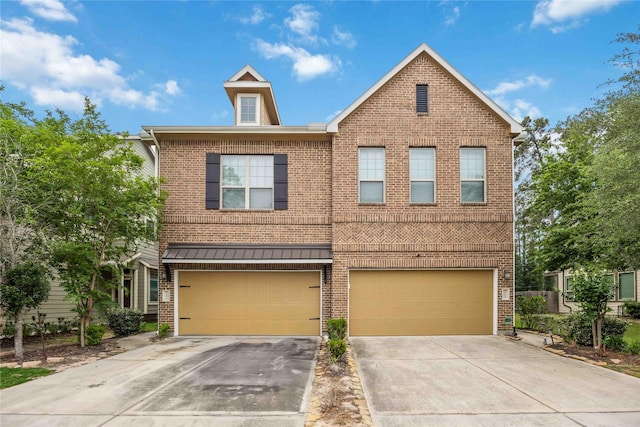 townhome / multi-family property with concrete driveway, an attached garage, brick siding, and a standing seam roof