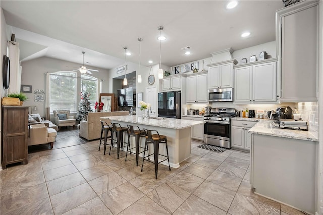kitchen featuring open floor plan, ceiling fan, light stone countertops, a breakfast bar, and appliances with stainless steel finishes