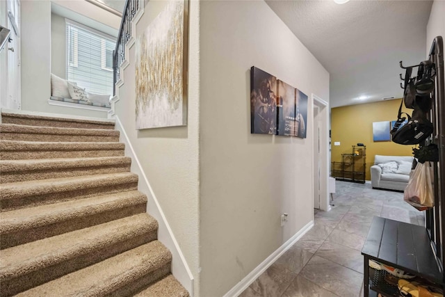 staircase with marble finish floor and baseboards
