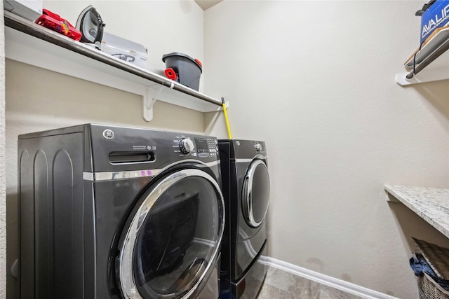 washroom with baseboards, washer and dryer, and laundry area