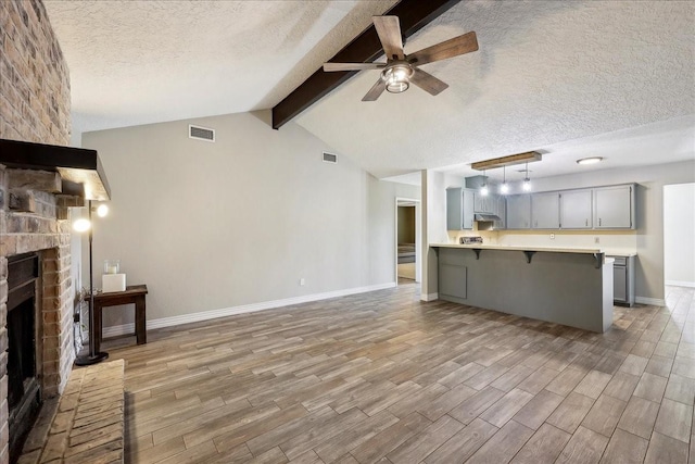 1117 Meadowland Dr, Beaumont, TX 77706 - unfurnished living room featuring a textured ceiling, light wood-type flooring, baseboards, ceiling fan, and a fireplace