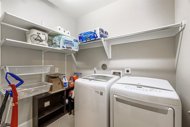 washroom with washing machine and clothes dryer, tile patterned floors, and laundry area