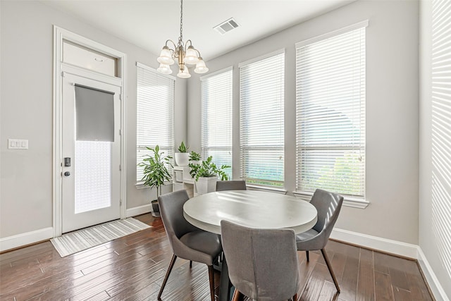 dining area with dark wood-type flooring, a chandelier, visible vents, and baseboards