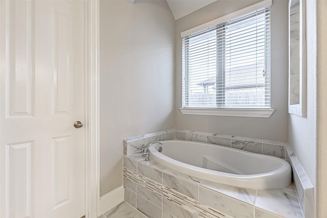 full bathroom featuring a bath and baseboards
