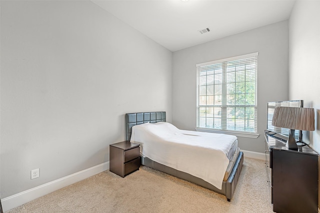 bedroom with baseboards, light carpet, and visible vents