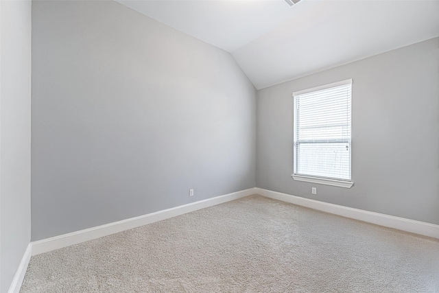 unfurnished room featuring lofted ceiling, light carpet, and baseboards