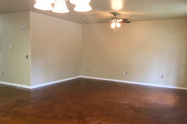 empty room featuring ceiling fan with notable chandelier, baseboards, finished concrete floors, and visible vents