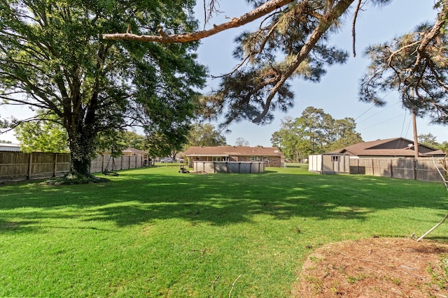 view of yard featuring a swimming pool, a fenced backyard, an outbuilding, and a shed