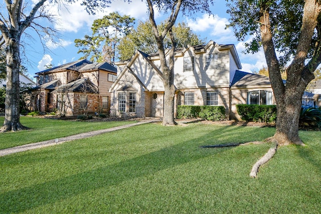 english style home with a front lawn and brick siding
