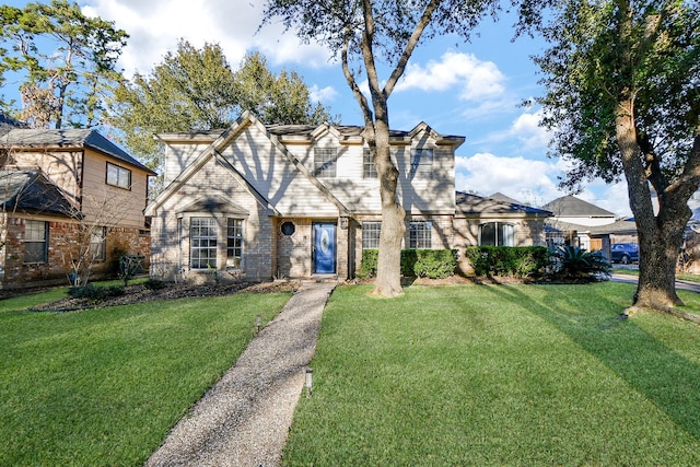 tudor home featuring brick siding and a front lawn
