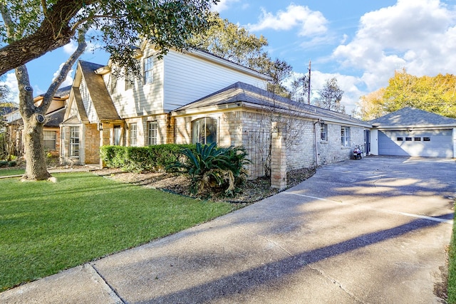 view of front of house with an outbuilding, a front lawn, concrete driveway, a garage, and brick siding