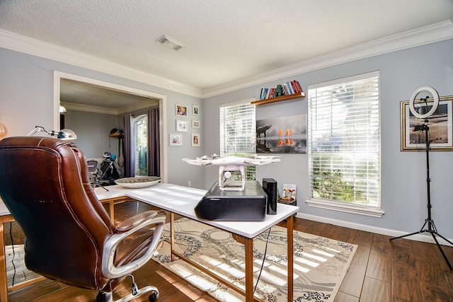 office space with a textured ceiling, baseboards, visible vents, wood finished floors, and crown molding