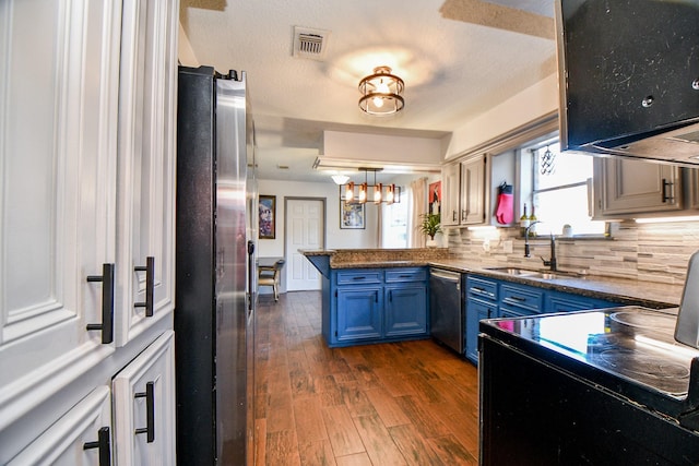 kitchen featuring stainless steel appliances, a peninsula, a sink, visible vents, and blue cabinetry
