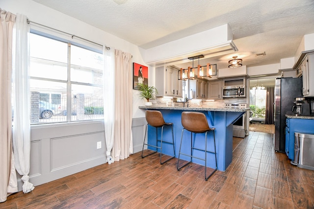 kitchen with open shelves, stainless steel appliances, a textured ceiling, and dark wood finished floors
