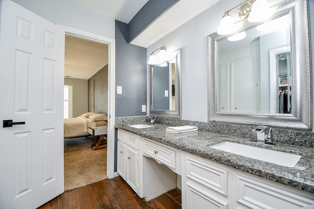 bathroom featuring wood finished floors, a sink, a textured ceiling, and double vanity