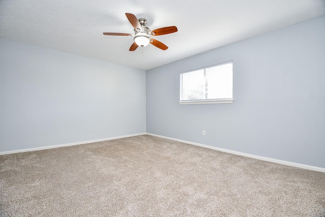 carpeted spare room with a ceiling fan and baseboards
