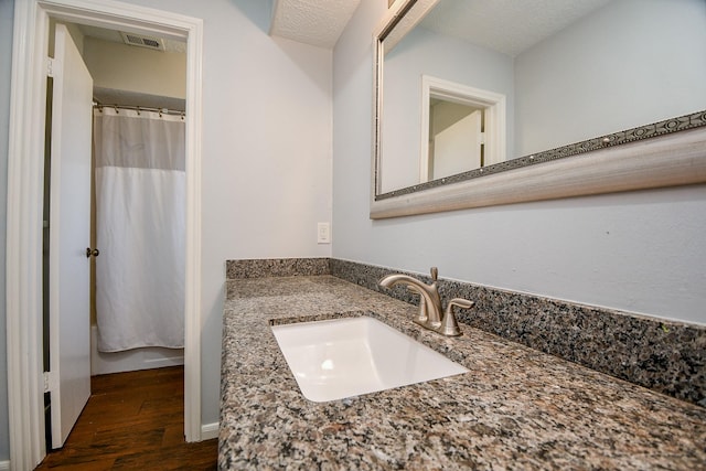 full bath with a shower with curtain, wood finished floors, visible vents, and vanity