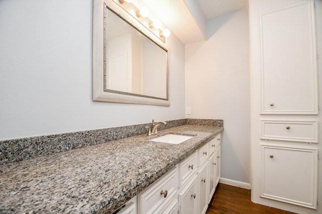 bathroom featuring baseboards, wood finished floors, and vanity