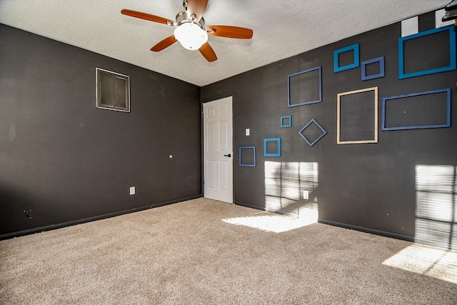 unfurnished room with a textured ceiling, baseboards, visible vents, carpet, and a ceiling fan