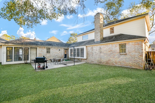 rear view of property with brick siding, a yard, a chimney, and fence