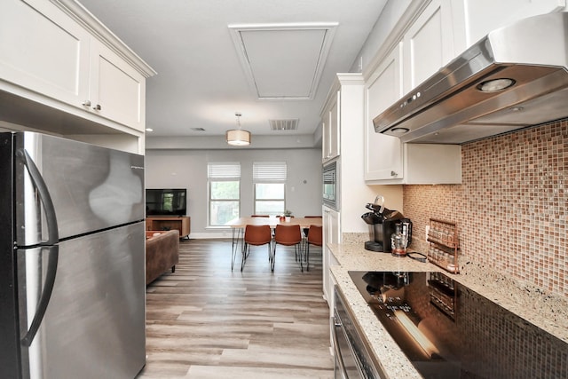 1561 Scharpe St, Houston, TX 77023 - kitchen featuring white cabinets, stainless steel appliances, light wood-style flooring, decorative backsplash, and exhaust hood