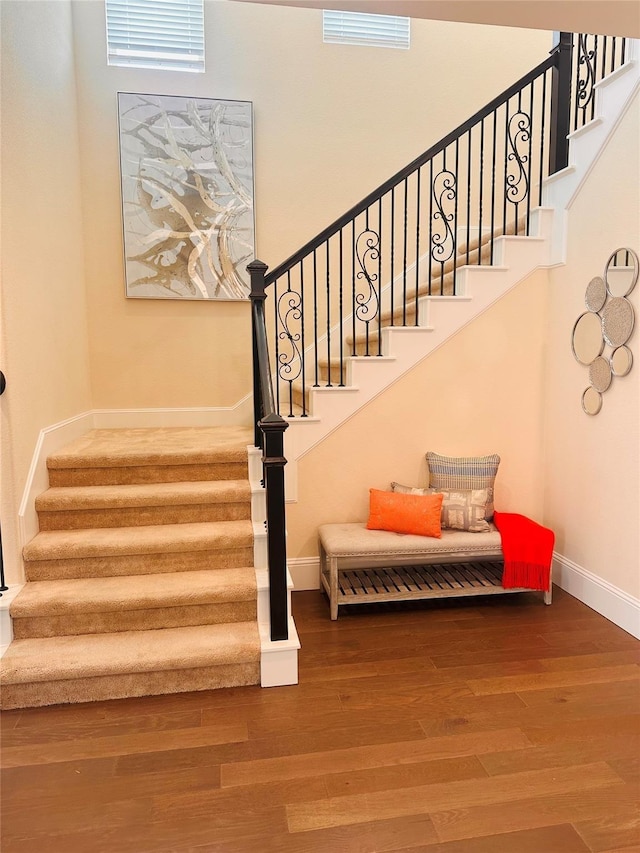 stairs with wood finished floors, visible vents, and baseboards