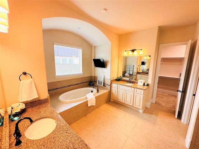 full bathroom with a walk in closet, a bath, tile patterned floors, and vanity