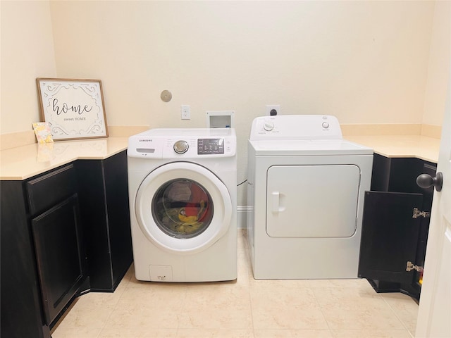 laundry room featuring washer and dryer, cabinet space, and light tile patterned floors
