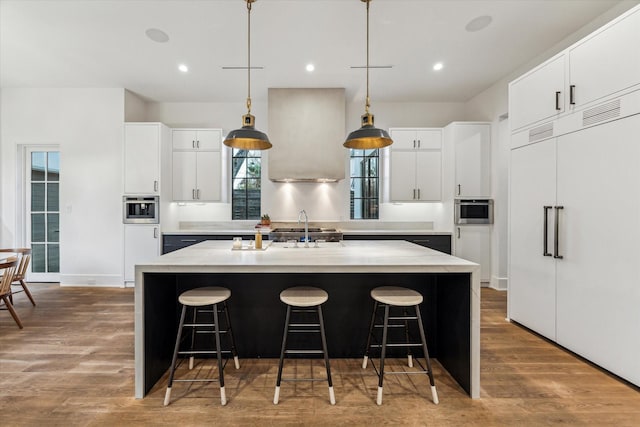 2926 Wroxton Rd, West University Place, TX 77005 - kitchen featuring paneled built in refrigerator, an island with sink, a breakfast bar, wood finished floors, and recessed lighting