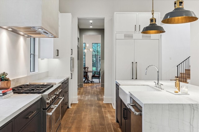 2926 Wroxton Rd, West University Place, TX 77005 - kitchen with double oven range, wall chimney range hood, dark wood-style floors, an island with sink, and light stone counters