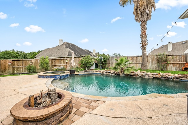 view of swimming pool featuring a fenced backyard, a patio area, a pool with connected hot tub, and a fire pit