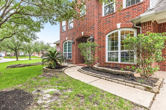 entrance to property featuring brick siding and a yard