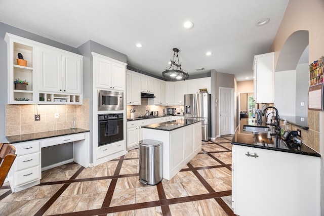 kitchen featuring a sink, dark countertops, stainless steel appliances, and under cabinet range hood