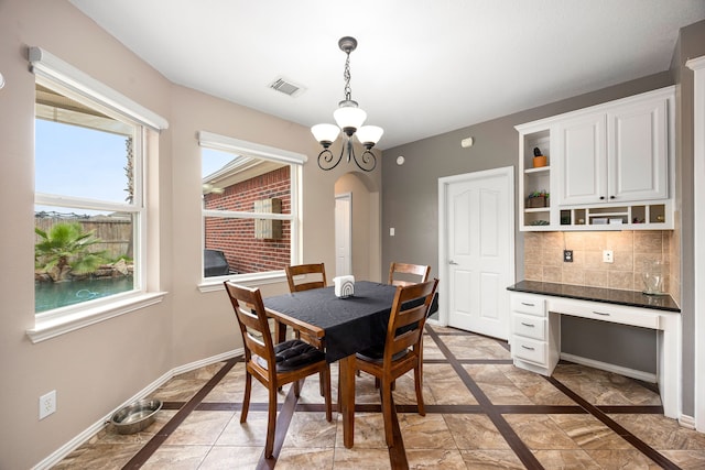 dining room with arched walkways, plenty of natural light, baseboards, and visible vents