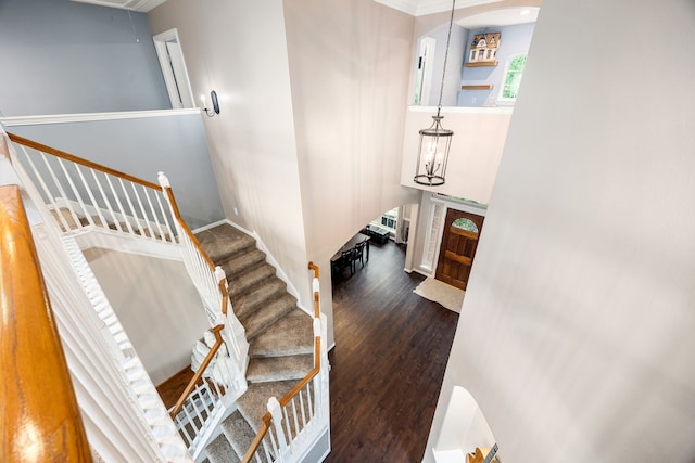 staircase featuring baseboards, attic access, wood finished floors, and ornamental molding